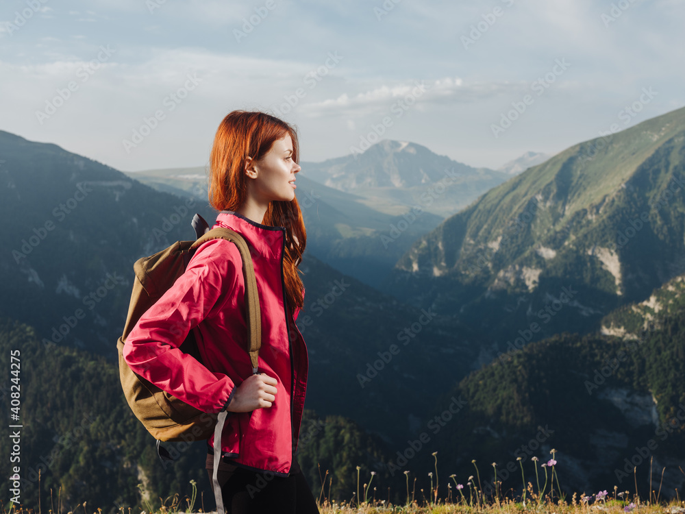 Traveler in a pink jacket with a backpack on her back in the mountains in nature