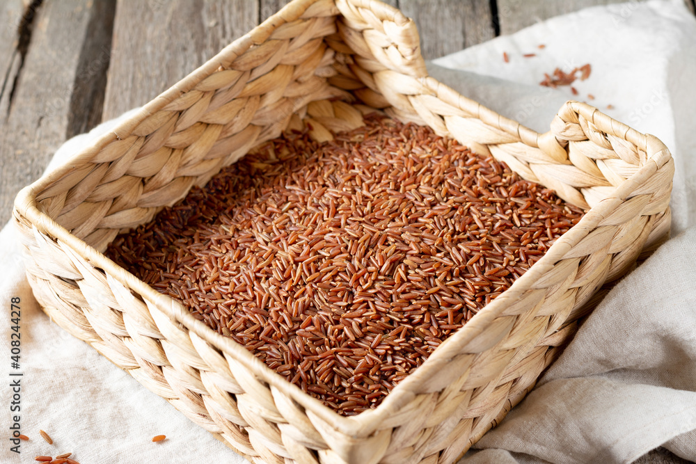 Red rice in a basket on a wooden table. Rustic style