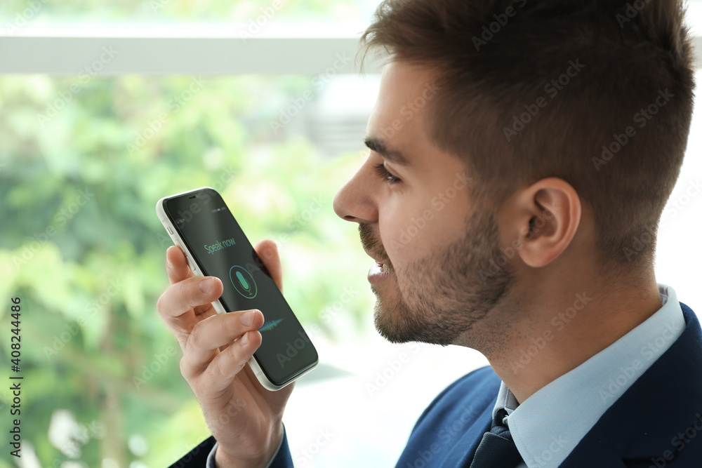 Young man using voice search on smartphone indoors Young man using voice search on smartphone indoors