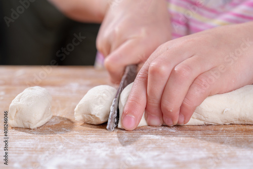 Cut the dough for the homemade pasta. Woman cuts the dough with a knife on wooden table