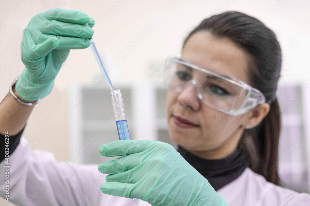 A female scientist in the laboratory examines a vaccine in a test tube. Creating a vaccine in the laboratory. A female scientist in the laboratory examines a vaccine in a test tube. Creating a vaccine in the laboratory.