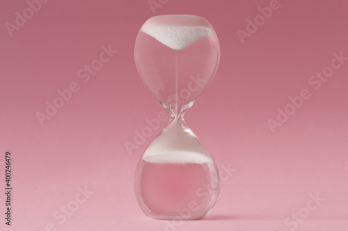 Upside-down hourglass on pink background - Concept of reverse time photo