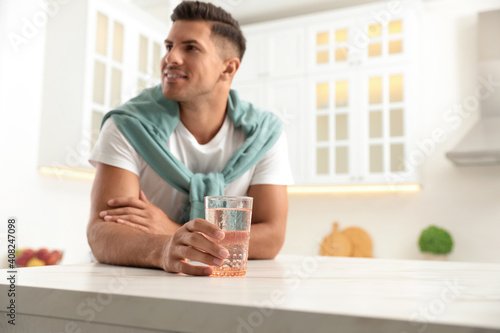 Wallpaper Mural Man holding glass of pure water at table in kitchen, focus on hand Torontodigital.ca