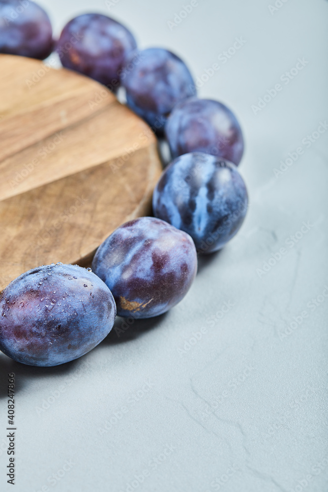 Obraz premium Group of fresh plums around the wooden plate