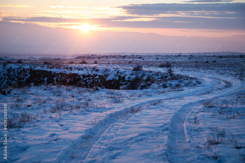 Snowy road in winter at sunset