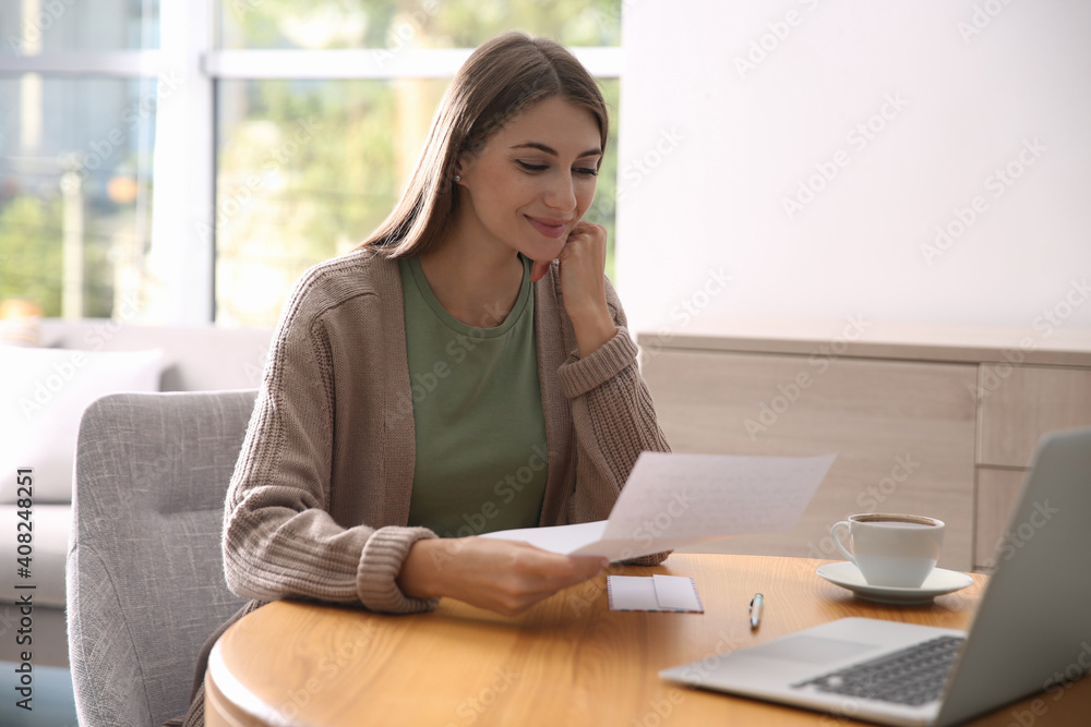 Woman reading letter at wooden table in room Woman reading letter at wooden table in room