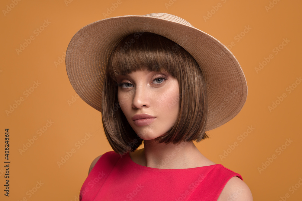 Portrait of a beautiful brown-haired woman in a hat on a yellow background. Portrait of a beautiful brown-haired woman in a hat on a yellow background.