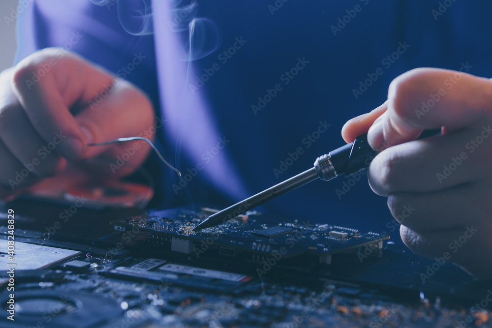 hardware maintenance and repair. electronics and computer components renovation. engineer soldering broken motherboard hardware maintenance and repair. electronics and computer components renovation. engineer soldering broken motherboard