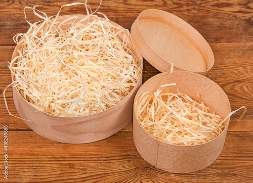 Round wooden boxes with wooden packing shavings on rustic table