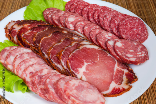 Sliced dry cured pork and different sausages closeup, selective focus
