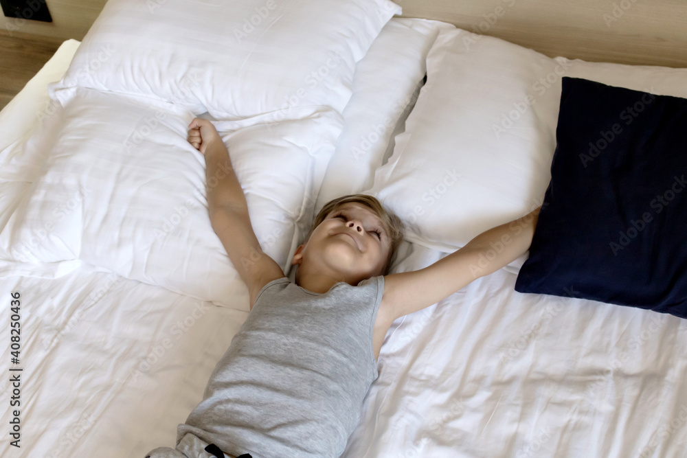 Above view of a kid stretching on a bed at home. Above view of a kid stretching on a bed at home.