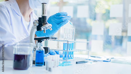 Medical or scientific researcher or man doctor looking at a test tube of clear solution in a laboratory