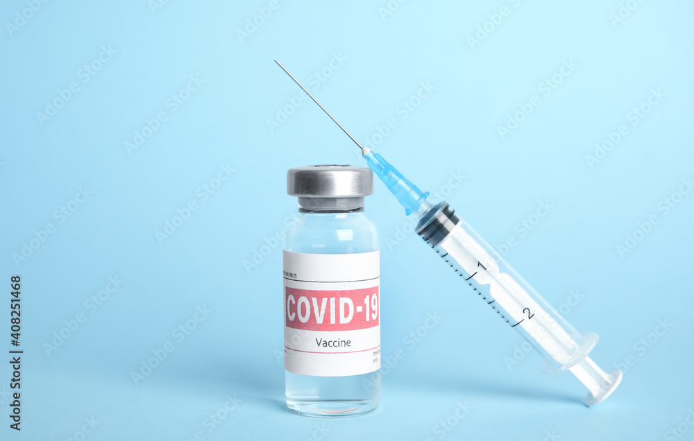 Vial with coronavirus vaccine and syringe on light blue background Vial with coronavirus vaccine and syringe on light blue background