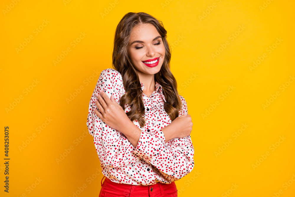 Portrait of positive pretty person closed eyes hug shoulder heart print clothing isolated on yellow color background Portrait of positive pretty person closed eyes hug shoulder heart print clothing isolated on yellow color background