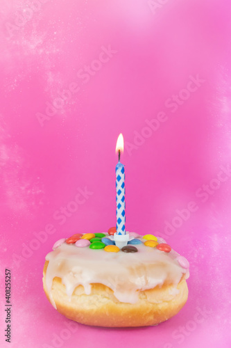 Delicious birthday cake with a burning candle, pink background with copy space