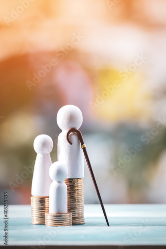 Family put on the gold coin and patriarch use the wooden walking cane put on the vintage blue wooden board  in the public park, Saving money for retirement and planning in the future concept.