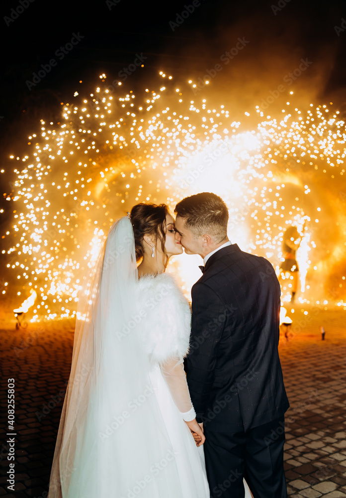 Newlyweds kiss on the background of fireworks in the evening