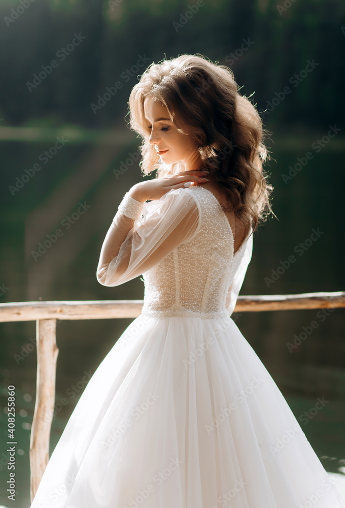 Tender bride in a luxurious wedding dress enjoys the views of a mountain lake Tender bride in a luxurious wedding dress enjoys the views of a mountain lake