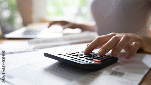 Calculating expenses. Close up of young female hand counting on portable electronic calculator estimating money income. Housewife planning family budget or managing payments for utility services.