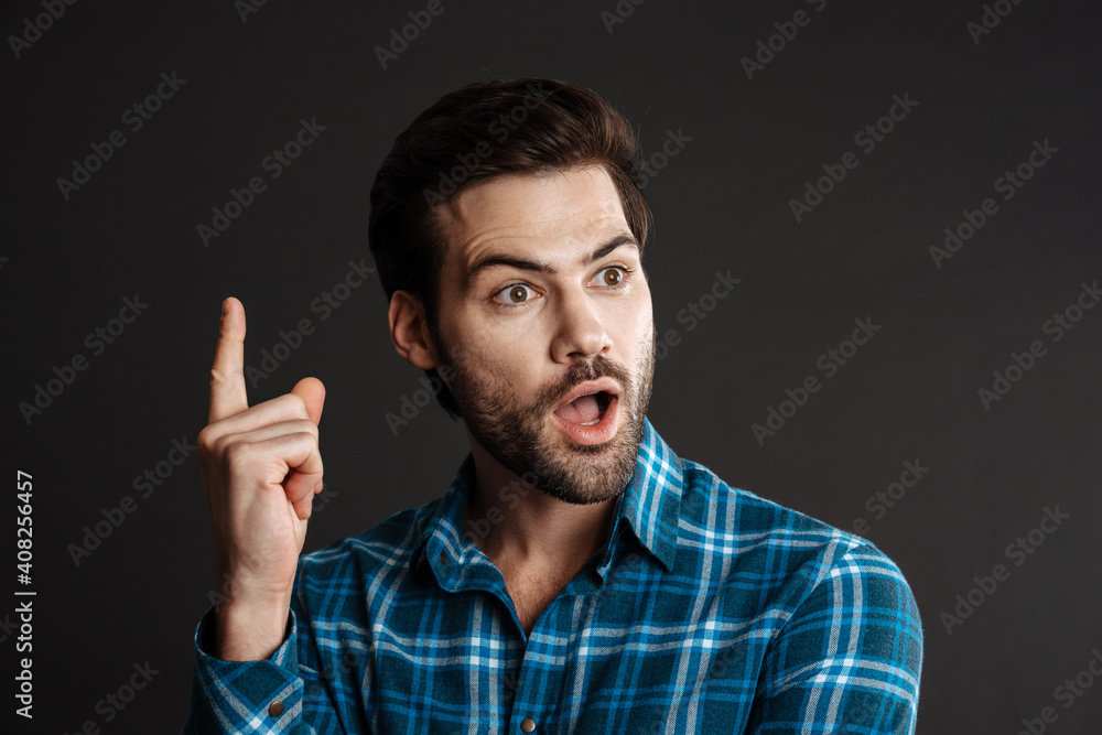 Shocked handsome guy exclaiming and pointing finger upward Shocked handsome guy exclaiming and pointing finger upward