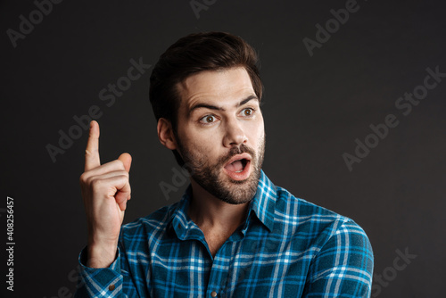 Shocked handsome guy exclaiming and pointing finger upward