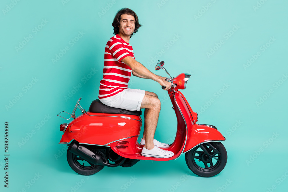 Profile side view portrait of handsome cheery guy driving moped highway isolated over bright green turquoise color background Profile side view portrait of handsome cheery guy driving moped highway isolated over bright green turquoise color background