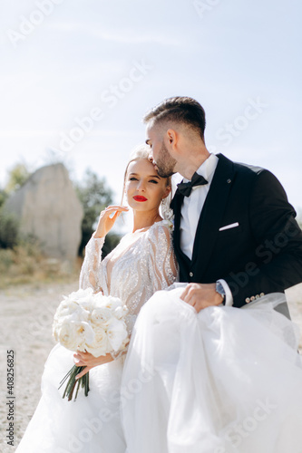 Fashion and stylish close-up portrait of beautiful newlyweds on a walk near the rocks