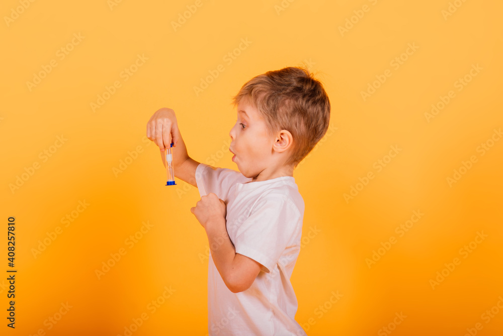 Kid time concept - serious male preschooler enjoying learning about time, holding an hour glass, studio shot Kid time concept - serious male preschooler enjoying learning about time, holding an hour glass, studio shot