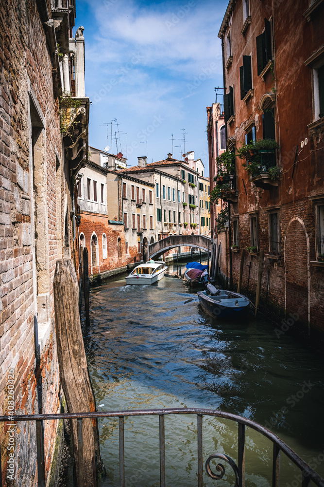 Venetian canal with a boat passing by. arch-type footbridge across the canal