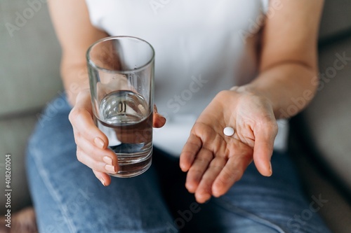 Top view of female hands with pill and water. Pain-relieving pill or enzyme in one hand of a woman and a glass of clean water in the other photo