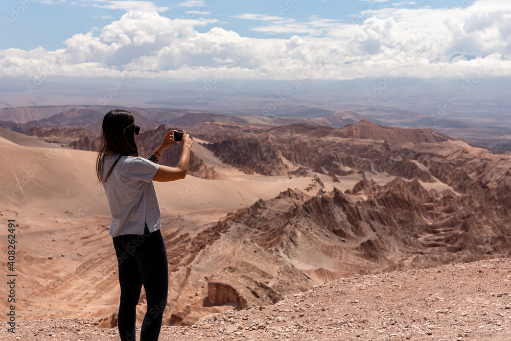Anonymous female traveler taking pictures of rocky formations on cloudy day in Atacama Desert, Chile