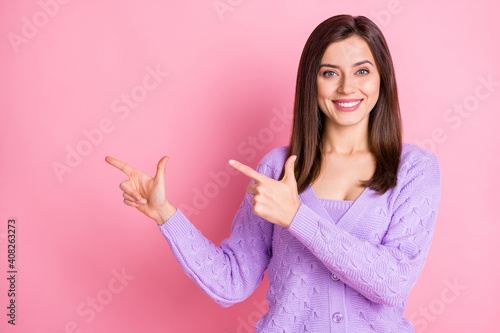 Portrait of optimistic girl point empty space wear lilac sweater isolated on pink color background © deagreez