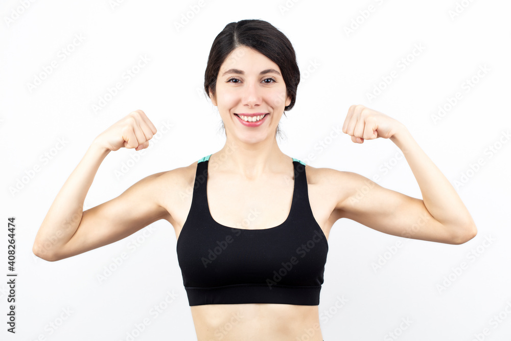 Young woman biceps in fitness wear isolated on white background.
Young woman biceps in fitness wear isolated on white background.