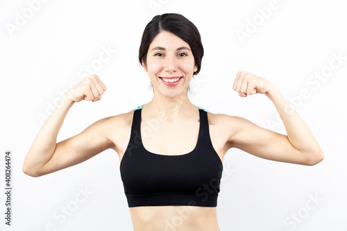 Young woman biceps in fitness wear isolated on white background.  © Emir