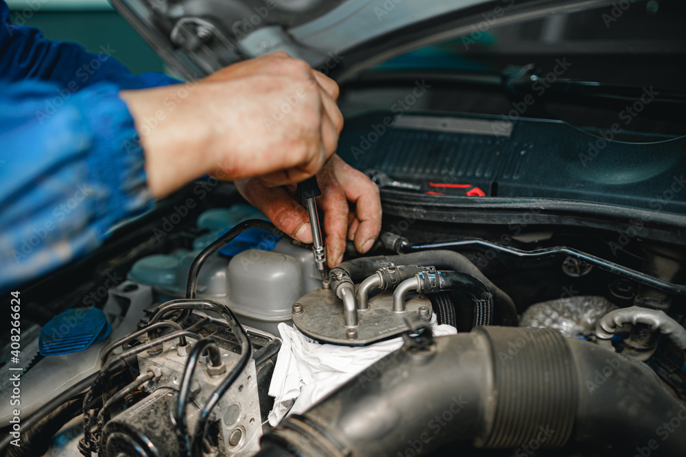 Auto mechanic man checks car engine under the hood Auto mechanic man checks car engine under the hood