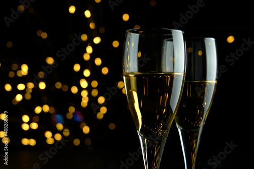 Two glasses of sparkling wine or champagne to celebrate Party or Anniversary with a yellow bokeh effect on dark background. 