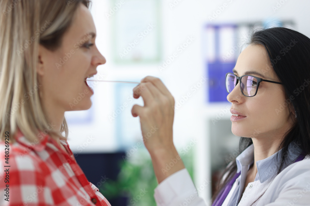 An otolaryngologist examines the patient's throat closeup An otolaryngologist examines the patient's throat closeup