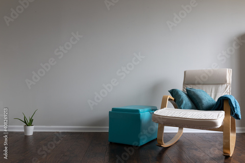 Relax atmosphere room with hardwood parquet floor and celery colored wall with a rocking chair and teal color thrown blanked placed on the armrest. Cactus and an ottoman.
