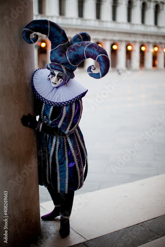 Foto Masked man in character of harlequin at the the Venetian masquerade peek out fro