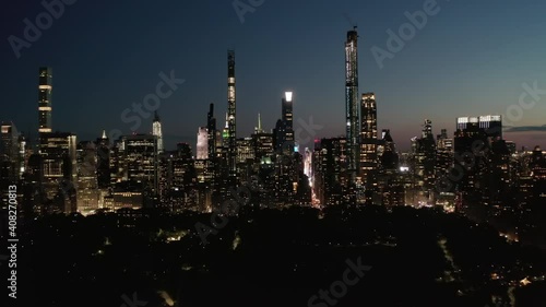 Moving Time Lapse Hyper Lapse over New York City Central Park at Night Towards Skyline of Manhattan Skyscraper with glowing City lights, Aerial Hyperlapse