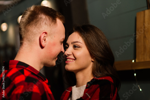 Young guy kissing her lovely girlfriend feeling happiness while celebrating winter holidays together