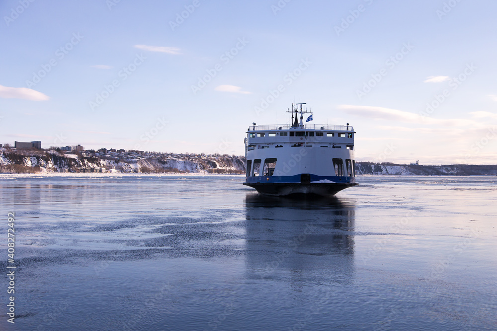 Obraz premium The ferry across the St. Lawrence River arriving at Quebec City from Levis during a cold clear winter afternoon, Quebec, Canada