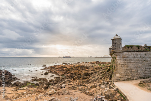 Sunset over the Atlantic ocean. Medieval watchtower of fort of Sao Francisco do Queijo in Porto, Portugal, frequently shortened to Castle of the Cheese, 15th century