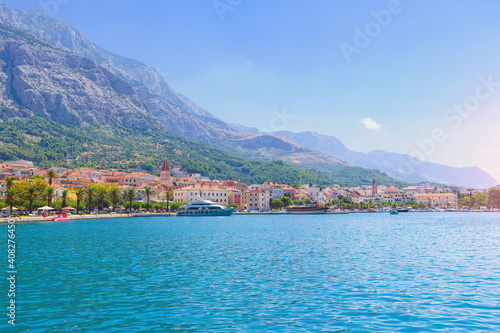 Sailing boat anchoring in Baška Voda town with historic buildings in background