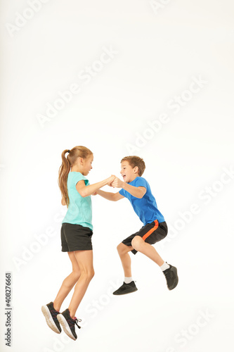 Cute kids holding hands and jumping together in studio