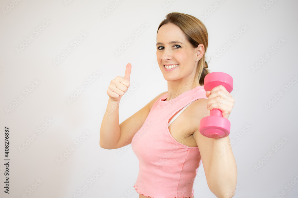 Smiling blonde woman holding dumbbell over white background. Smiling blonde woman holding dumbbell over white background.