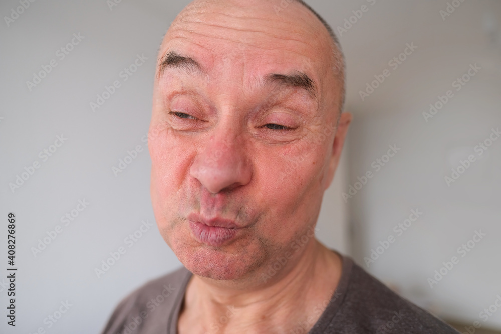 Obraz premium face of a European old man close up, wrinkles on the aging skin, bares teeth, makes grimaces, the concept of mental health, cosmetology, age-related changes