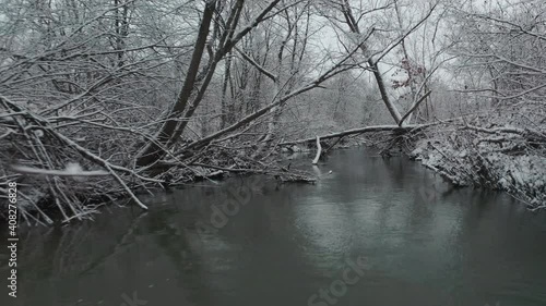 backward drone flight above the misty river through trees and branches in winter morning and above the mountains