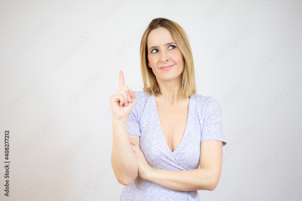 Smiling woman pointing up with index finger standing over white background. Smiling woman pointing up with index finger standing over white background.