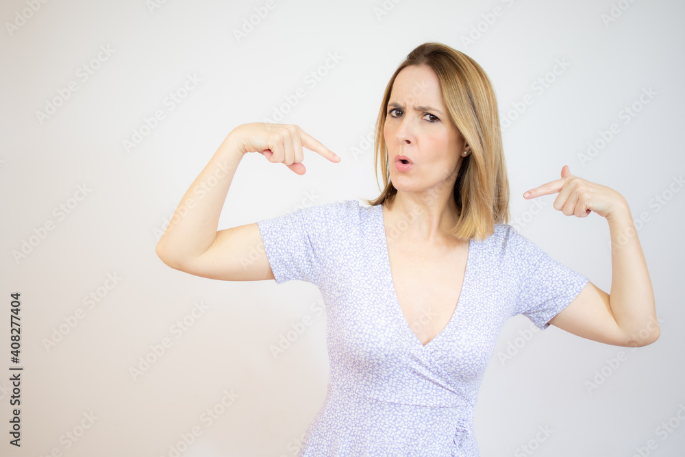 Young woman in casual dress standing, pointing herself with serious face and looking at camera. Young woman in casual dress standing, pointing herself with serious face and looking at camera.